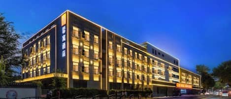 A multi-story hotel with a modern facade, multiple windows, and a well-lit entrance.