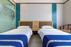 A hotel room with two beds, a wooden headboard, and a chair.