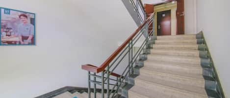 Una escalera con barandilla, escalones alfombrados y un letrero en la pared.