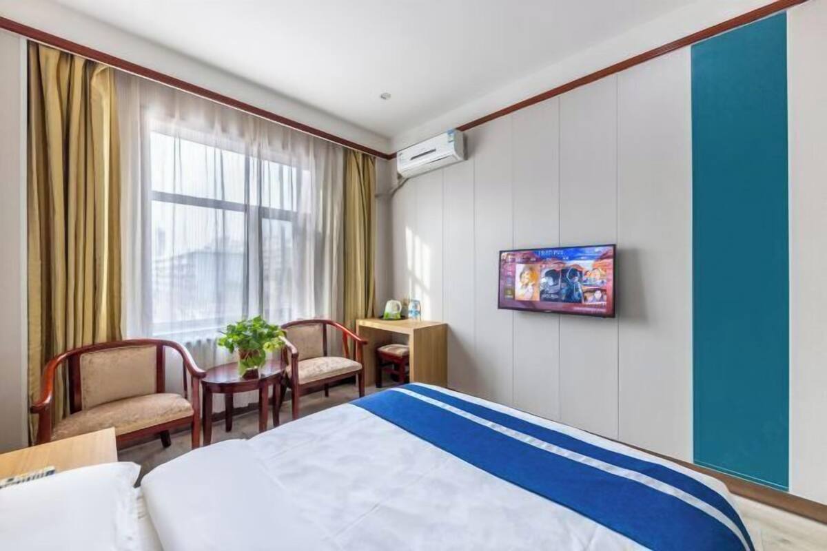 A hotel room with a bed, a desk, a chair, a television, and a window with curtains.