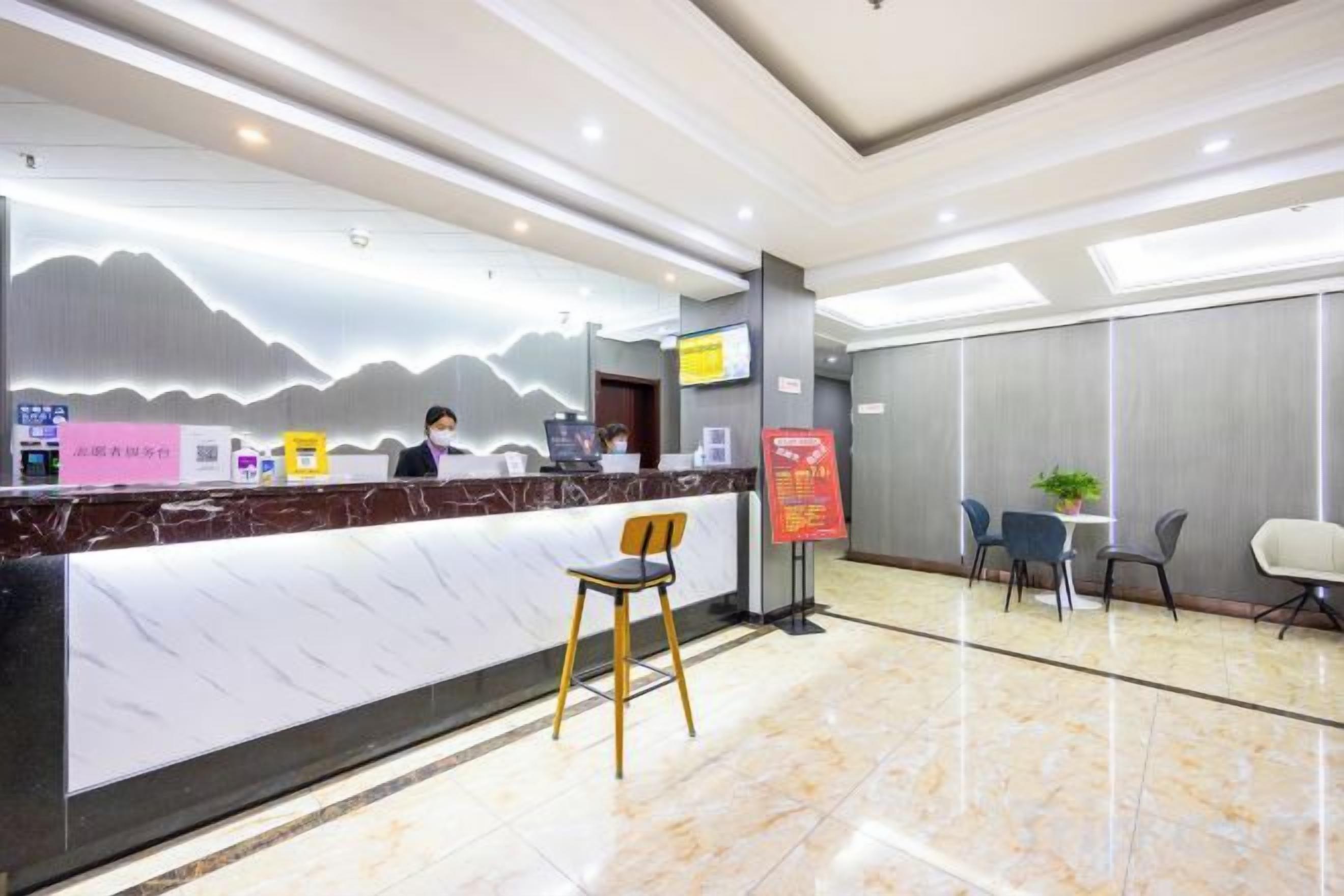 A hotel reception area with a marble counter, a receptionist, and seating arrangements.