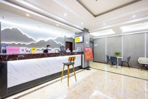 A hotel reception area with a marble counter, a receptionist, and seating arrangements. - Kaida Xinyu Hotel (Lanzhou Jiaotong University Anning Government Branch) (Lanzhou)