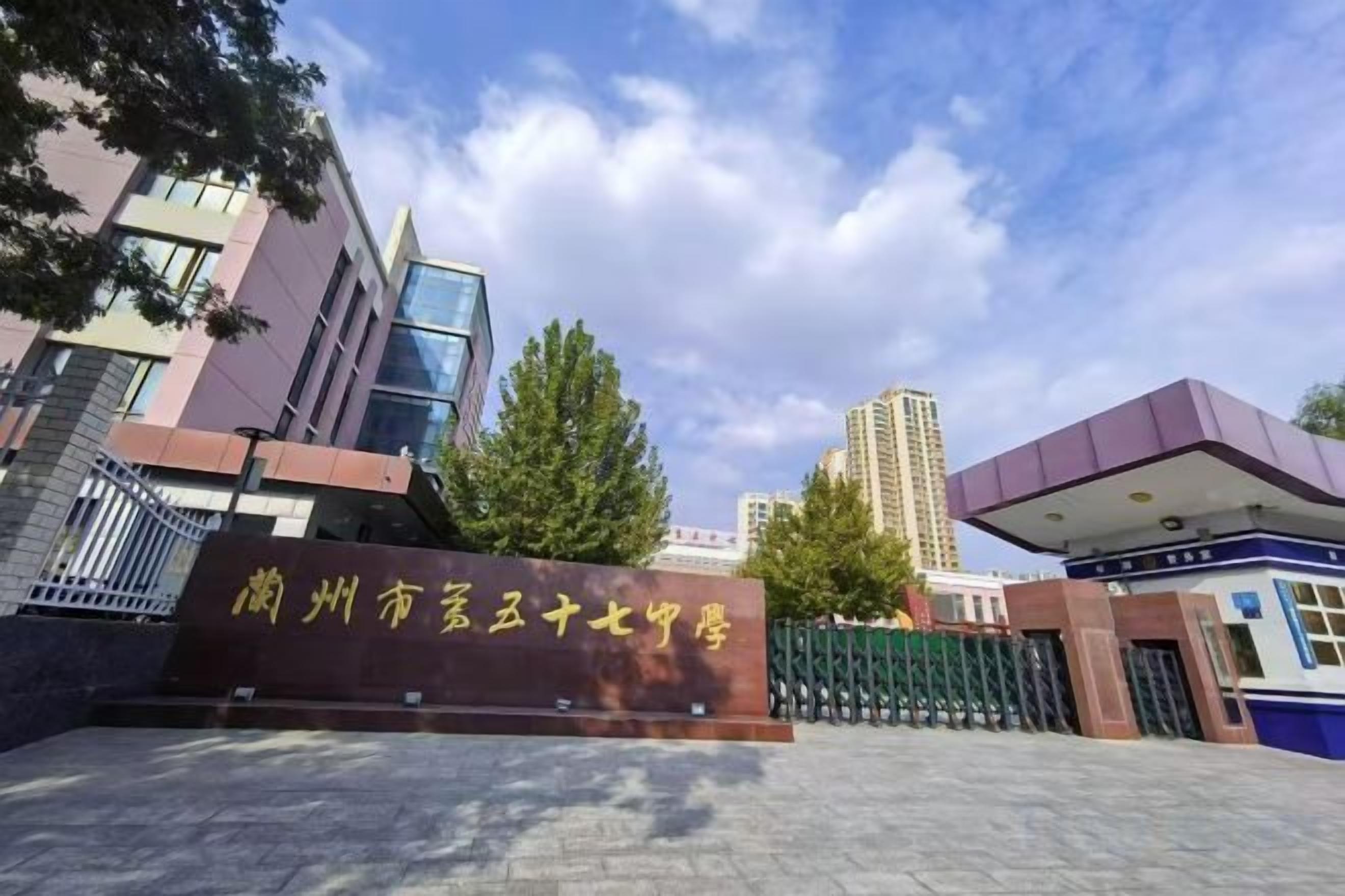 A building entrance with a sign, a gated area, and a clear sky.