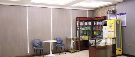 A hotel lobby with a seating area, vending machines, and a glass display case.