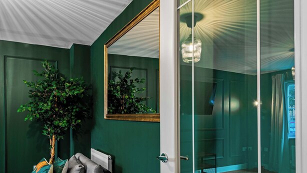 A room with a green wall, a large mirror, a potted plant, and a modern light fixture. - Whitley Rise, Reading (Berkshire)
