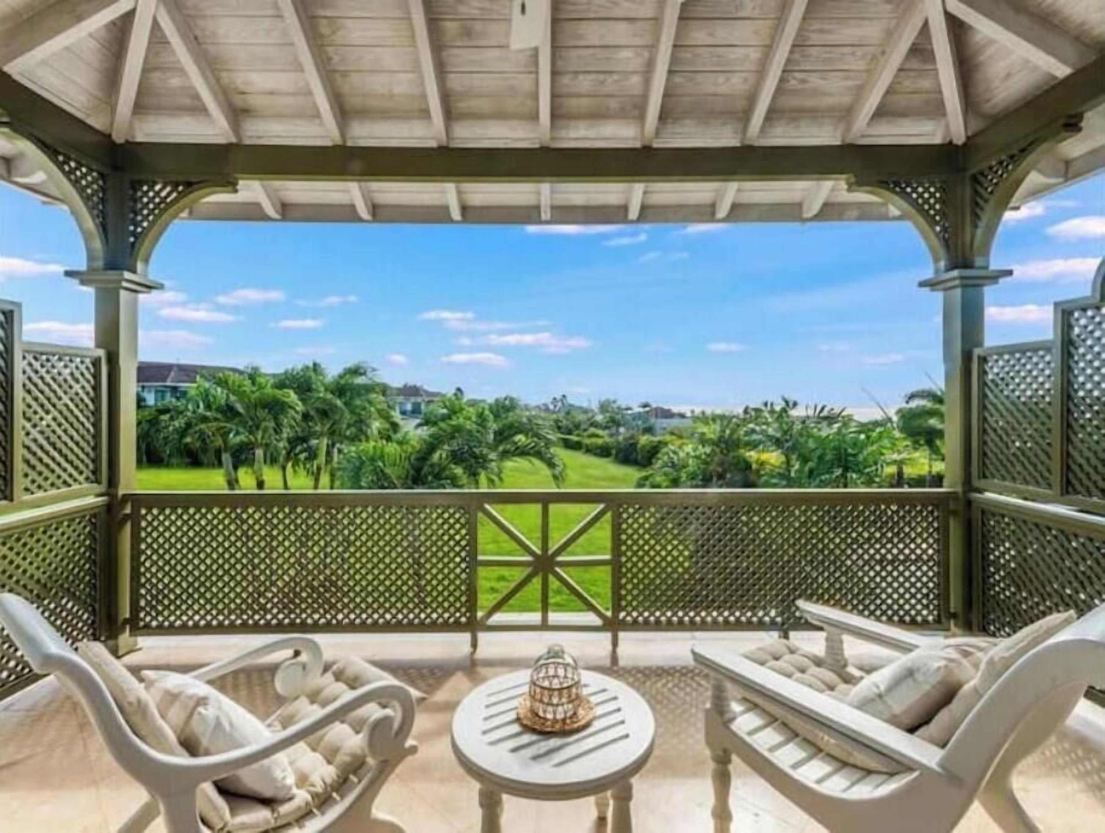 A covered outdoor seating area with a view of a well-maintained lawn and distant buildings.