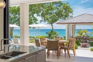 Une cuisine avec vue sur l’océan, un espace repas extérieur et une piscine.