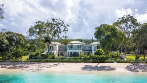 Une propriété située en bord de mer, avec une grande maison moderne à plusieurs niveaux et dotée de larges fenêtres.