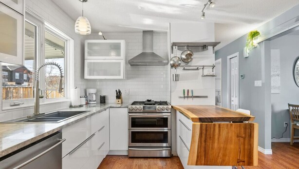 A modern kitchen with white cabinetry, stainless steel appliances, and a wooden island.