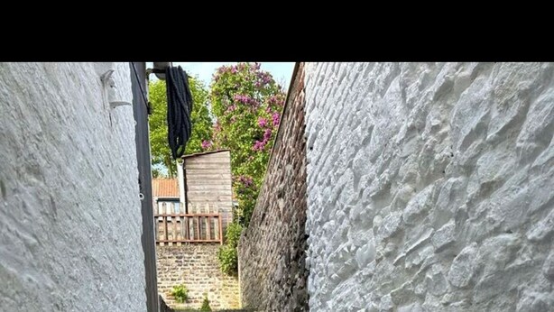 En smal stentrappe fører op til en bygning med hvide vægge.