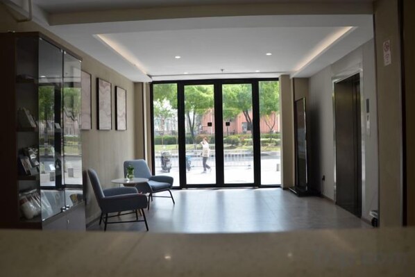 A spacious lobby with a seating area, a reception desk, and a large glass door leading outside. - Huayi Collection Hotel (Shanghai Jiuting Subway Station Jiudu Road) (Shanghai)