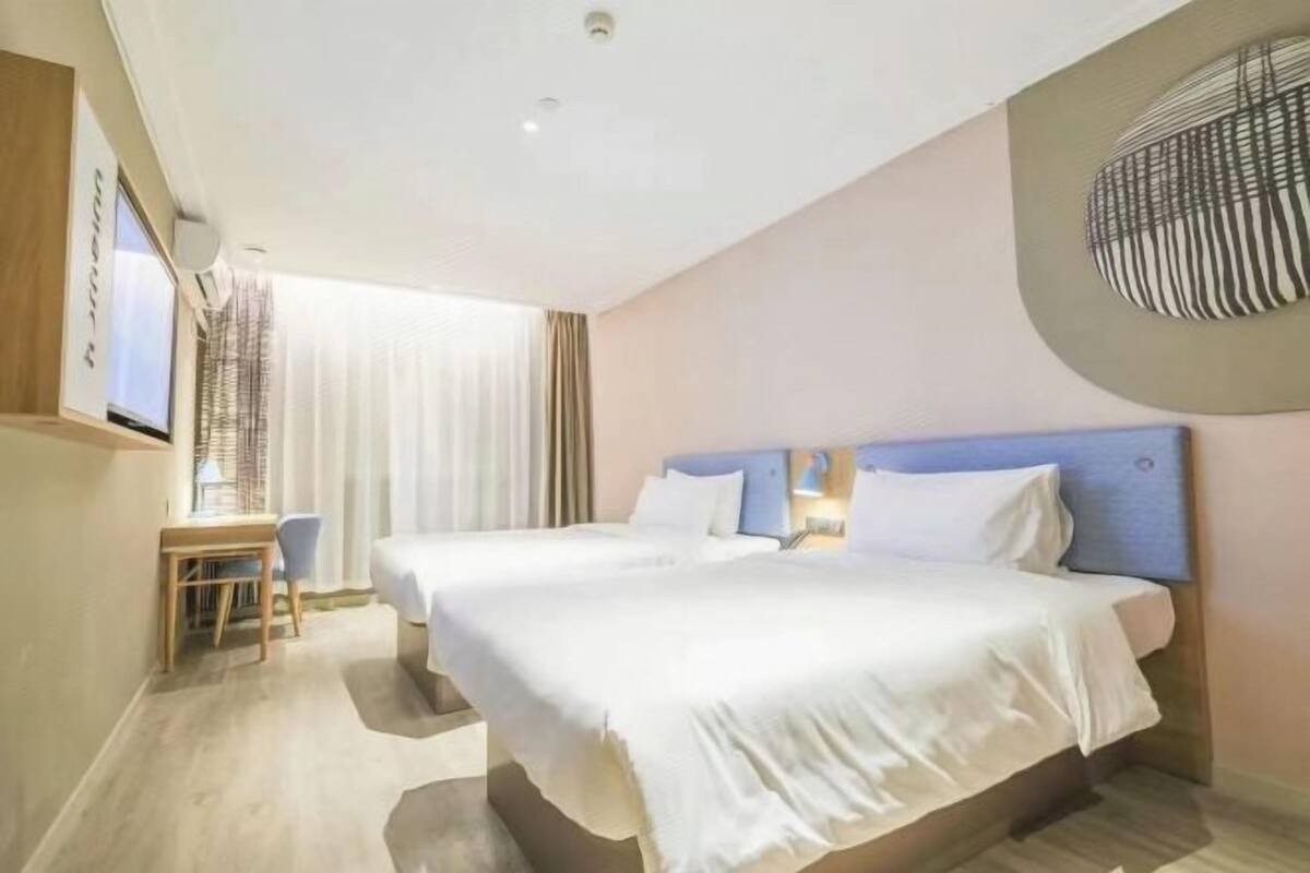 Habitació d'hotel amb dos llits, un escriptori i una televisió.