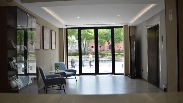 Un hall amplio con un gran ventanal que da al exterior, una zona de estar con sillones y un mostrador de recepción.