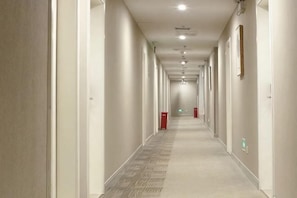 A long, narrow hotel corridor with doors on both sides, carpeted flooring, and recessed lighting on the ceiling. - Huayi Collection Hotel (Shanghai Jiuting Subway Station Jiudu Road) (Shanghai)