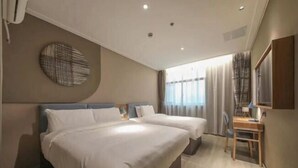 Habitación de hotel con dos camas, un escritorio, una silla, un adorno circular en la pared y una ventana con cortinas.