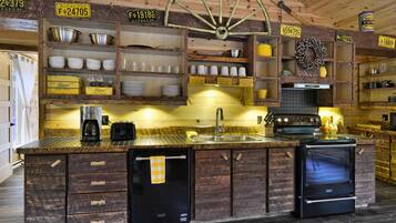 Una cocina rústica con armarios de madera, un refrigerador negro, una estufa y diversos utensilios de cocina.