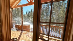 A wooden deck with a hot tub and a wooden railing. - Les Chalets de Môh  (La Malbaie)