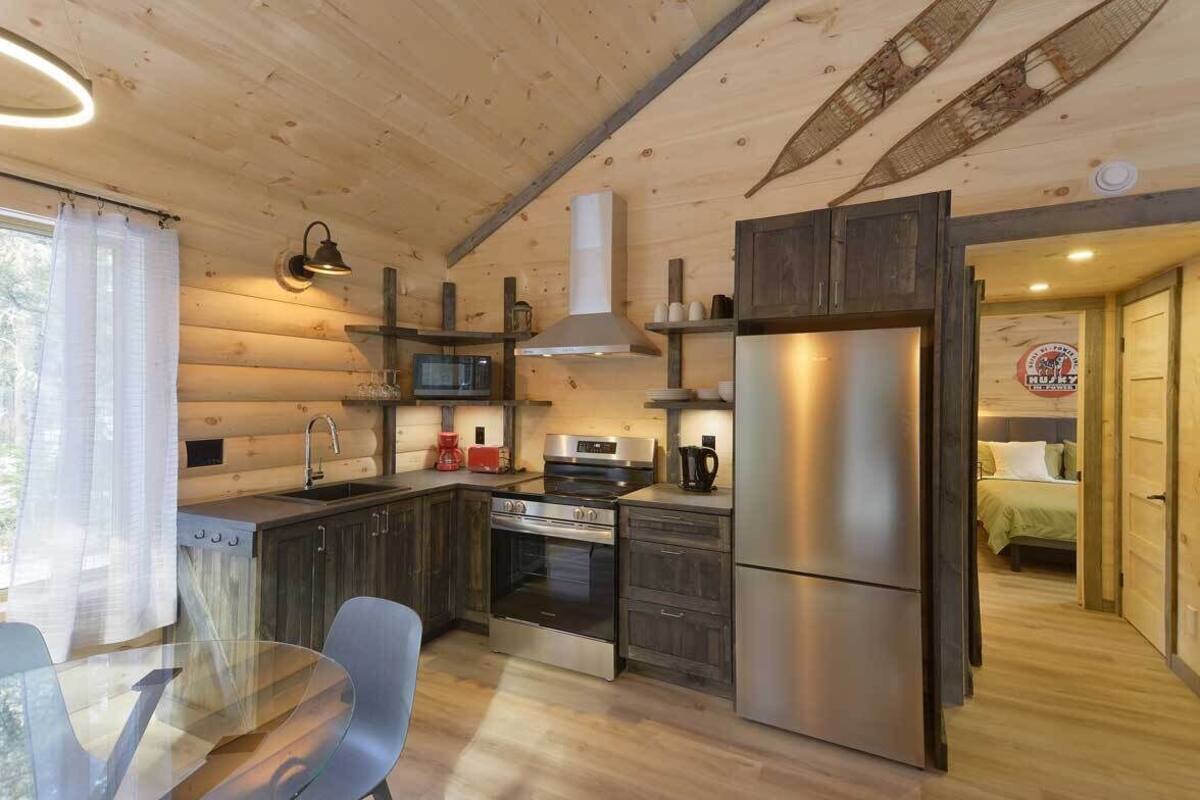 Une cuisine de taille réduite avec des murs en bois, un réfrigérateur en acier inoxydable, un four à micro-ondes et une cuisinière.
