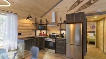 Una cocina compacta con paredes de madera, un refrigerador de acero inoxidable, un microondas y una estufa.