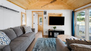Un salon moderne avec un canapé gris, une table basse en bois et un téléviseur fixé au mur.