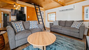 Un salon chaleureux avec deux canapés gris, une table basse en bois et un tapis bleu à motifs.