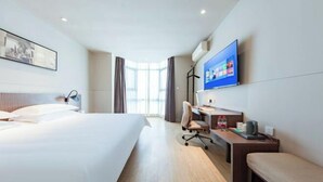 Une chambre d’hôtel avec un lit, un bureau, une chaise et un téléviseur fixé au mur.