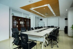 A conference room with a long table, black chairs, a whiteboard, and a bookshelf.