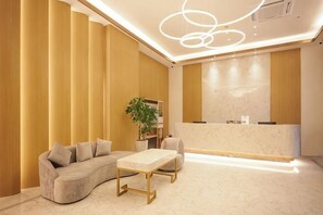 A modern reception area with a curved sofa, a marble coffee table, and a reception desk.
