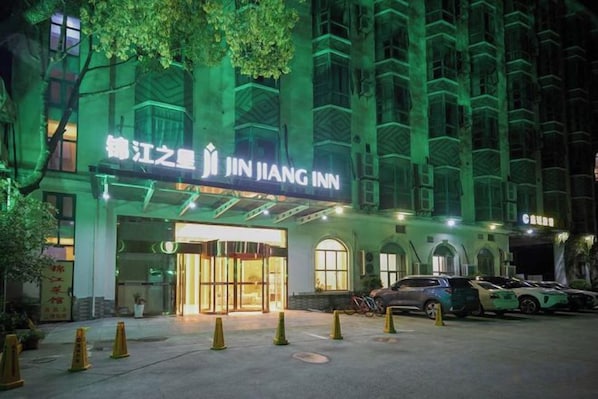 Entrada de un hotel con un letrero que dice 'JIN JIANG INN' y un camino de entrada con portón.