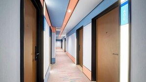 Corredor de hotel com piso coberto por carpete, portas em ambos os lados e uma placa azul indicando a suíte número 406.