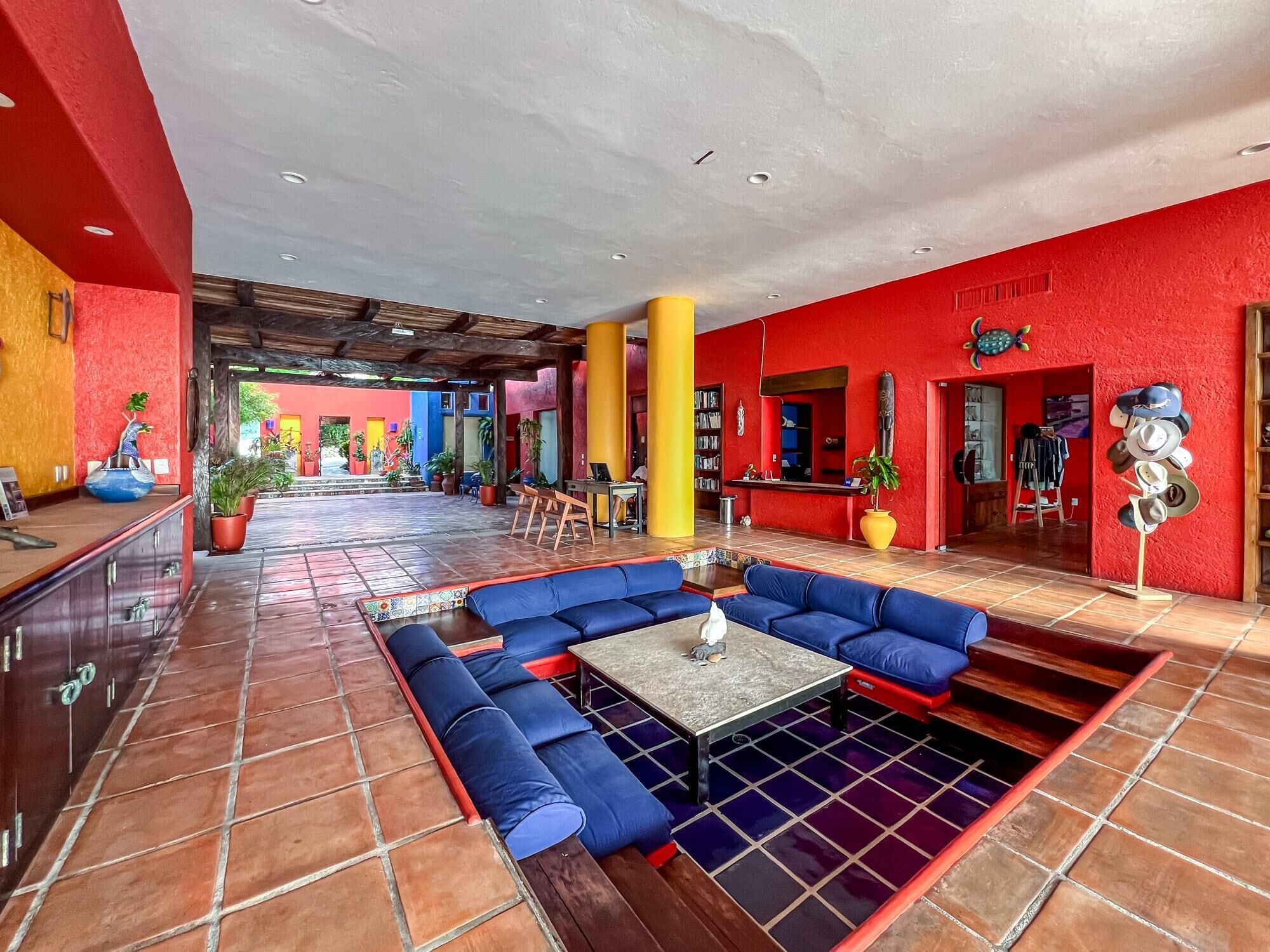 A spacious lobby with a central seating area, a reception desk, and a vibrant red and yellow color scheme.