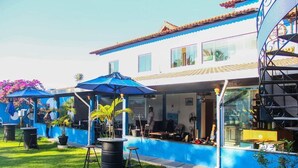 A building with a blue exterior, a pool, outdoor seating, and a staircase. - Pousada Paraiso Azul (Anchieta)