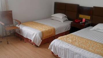 A hotel room with two beds, a desk, and a chair.