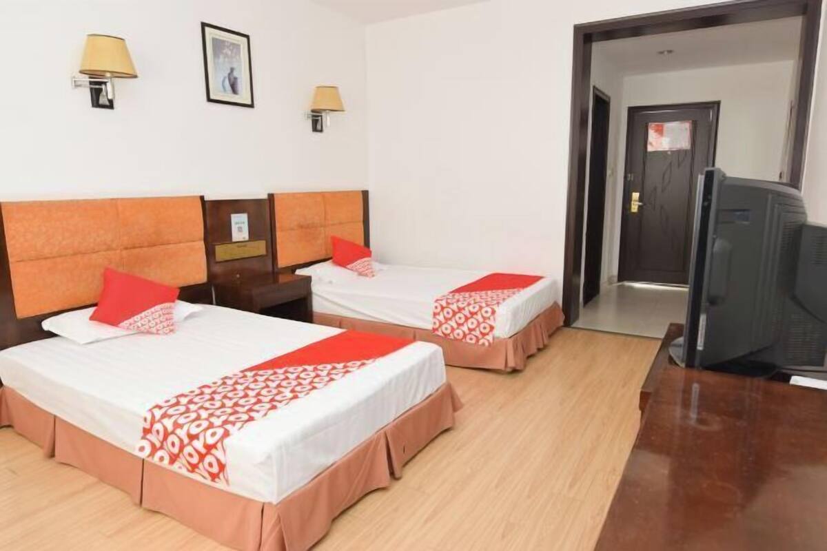 Een hotelkamer met twee bedden, een televisie en twee wandlampen.