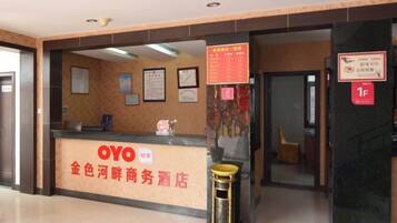 Een hotel receptiebalie met een bord voor OYO hotel, een prullenbak en een muur met ingelijste certificaten.