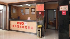 A hotel reception area with a reception desk labeled "OYO" and a sign indicating a 1F room. - Jinse Hepan Business Hotel (Tongcheng)