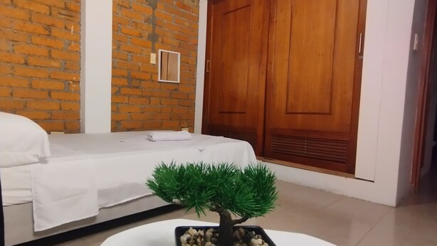 A room with a bed, a small potted plant, a wooden door, and a brick wall. - House in Santa Rosa de Cabal (Santa Rosa de Cabal)