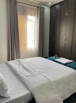 Simple, functional room with a single bed and dark wardrobe.