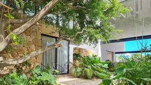 A modern building with a stone facade, a gravel pathway, and lush greenery. - Chic studio with WiFi and AC in vibrant Playa del Carmen, centric and OV rooftop (Playa del Carmen)