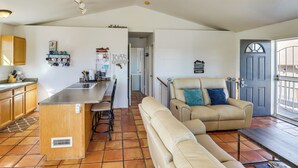 A spacious living area with a sofa, a coffee table, and a kitchen with a bar. - Firelit Nights By the Lake: Cozy Show Low Retreat (Show Low)