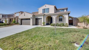A two-story house with a garage, a front yard, and a clear blue sky. - Luxurious & Spacious Family Duplex in Menifee! (Menifee)