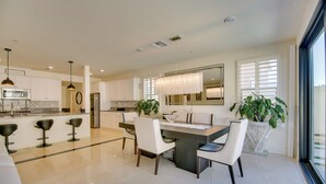 A modern kitchen with a central island, bar stools, and a dining area with chairs. - Luxurious & Spacious Family Duplex in Menifee! (Menifee)
