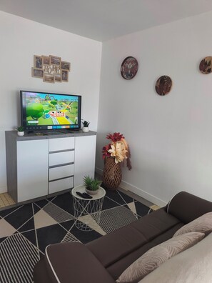 A modern living room with a flat-screen TV, a sofa, a coffee table, and decorative items.