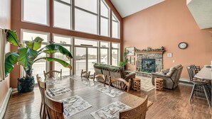 Un'ampia sala da pranzo con un grande tavolo di legno, numerosi posti a sedere e vista panoramica attraverso ampie finestre.