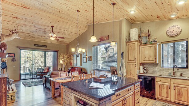 A spacious kitchen with wooden cabinets, a large island, and a dining area with chairs and a table. - Rustic Retreat w/ Spacious Deck in Show Low! (Show Low)