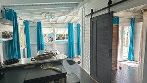 A spacious room with a large window, a ceiling fan, and a door leading to another area.