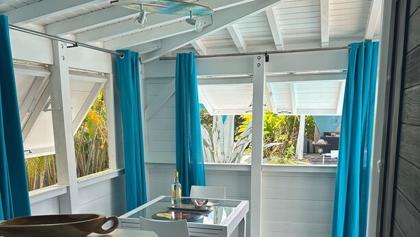 A compact kitchen with a dining area, featuring a glass table, white chairs, and a small trash bin.