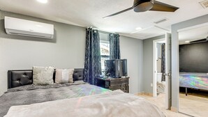 A bedroom with a bed, a ceiling fan, an air conditioning unit, a television, and a wardrobe. - 8 Mi to Sunset Beach: Home w/ Large Patio + Pool! (New Port Richey)