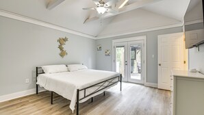 Un dormitorio con cama, ventilador de techo y puerta que da a un balcón.