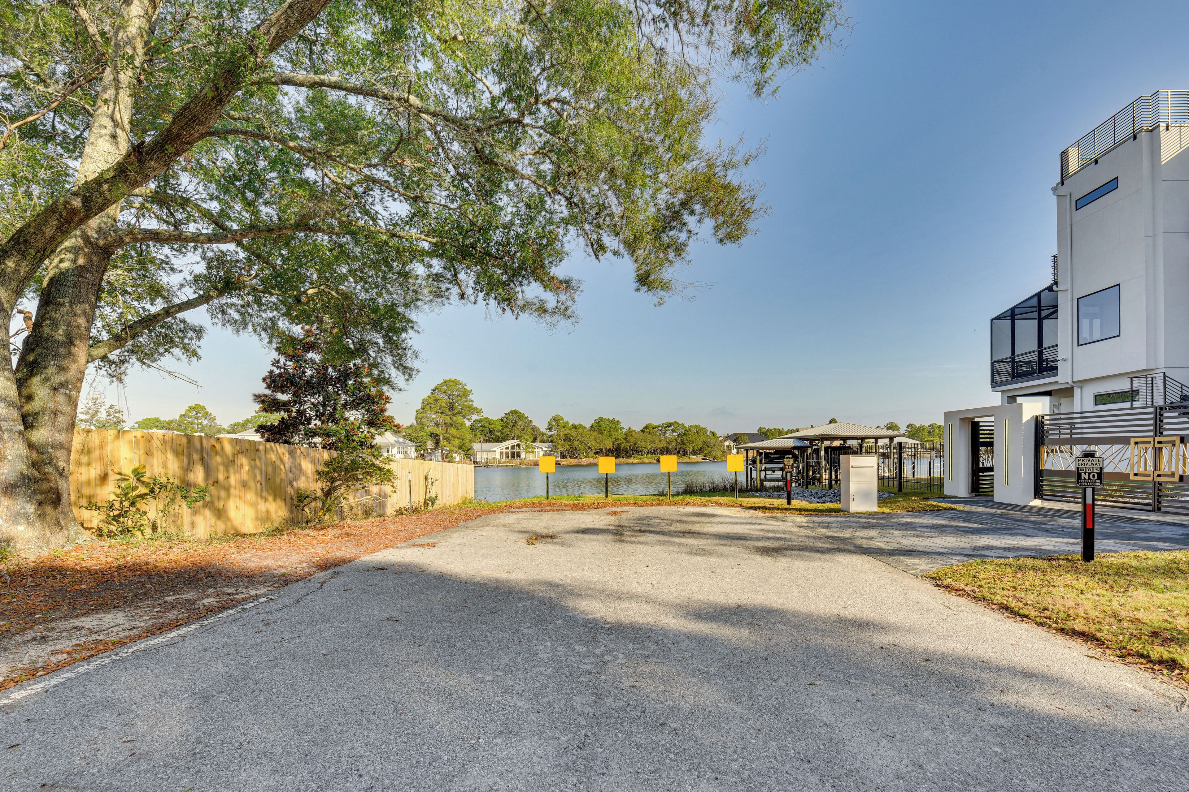 A modern building with a parking area, a covered walkway, and a body of water in the background.